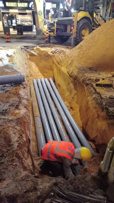 הנחת שרוולים לתשתיות יבשות בחפירה, עם עובד בווסט זוהר לצדם.