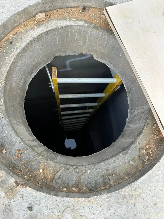 שוחת בטון טרום פתוחה עם סולם ירידה, לפני סגירתה.