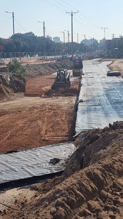 עבודות עפר בתוואי הרכבת הקלה: יריעות גיאוטכניות פרוסות בתחתית החפירה ומחפרון עובד ברקע.