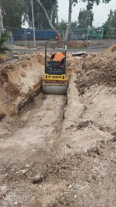 הידוק קרקעית התעלה במכבש קטן לפני המילוי החוזר.