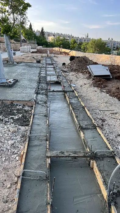 יציקת תעלת ניקוז מבטון לאורך התוואי, עם נוף ירושלים ברקע.