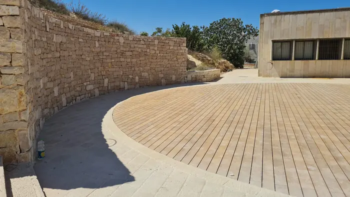 הרחבה המעגלית המוגמרת: קיר אבן מעוגל וריצוף בגוון עץ, מוכנה לשימוש הציבור.
