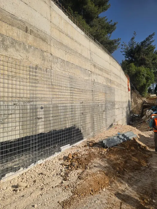 קיר תומך מחופה ברשת זיון לאורך המדרון, לפני יישום בטון מותז.