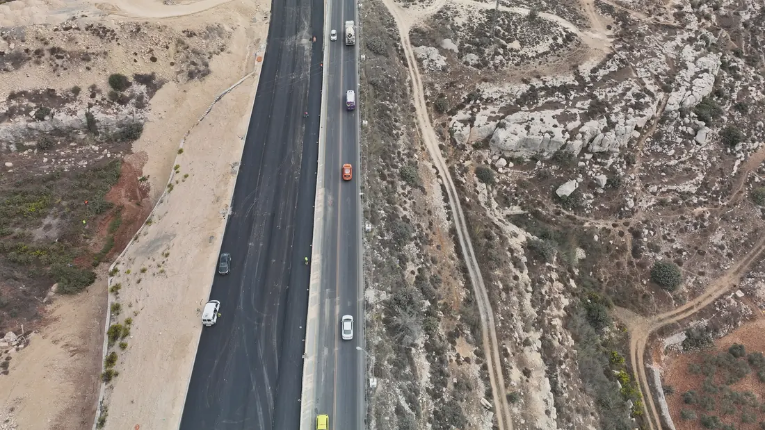 סלילת אספלט בכביש 60: נתיב חדש שנסלל במקביל לכביש הפעיל, עם קיר תומך לאורכו.