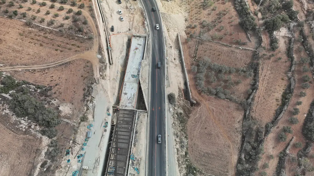 ביצוע מבנה גשר בצמוד לכביש הפעיל: תבניות ופלדת זיון לסיפון, ומתחם עבודה לצד הנתיב.