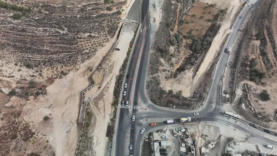 שדרוג צומת בכביש 60: מעברי חצייה מסומנים, כלי צמ״ה בעבודות עפר בצד אחד ומבנים בצד השני.